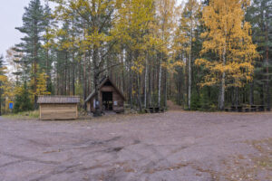 Parkering vid Trollegater med vindskydd, dass och picknickbord omgivna av höstfärgad blandskog med björkar och tallar