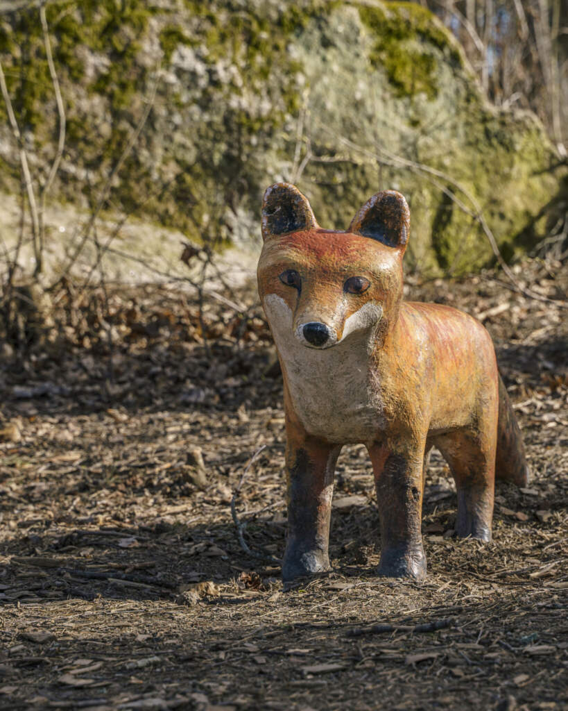 Skulptur av en räv i naturlig storlek längs en stig i Magistratshagens lekplats i Ekkällan, Linköping