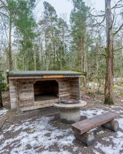 Ekängs vindskydd med grillplats och träbänk i snöklädd skog längs Östgötaleden vid Ekängsdalen, Linköpings kommun