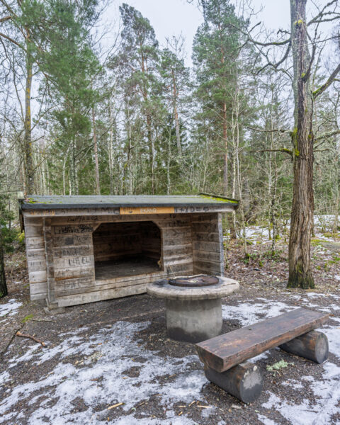 Ekängs vindskydd med grillplats och träbänk i snöklädd skog längs Östgötaleden vid Ekängsdalen, Linköpings kommun