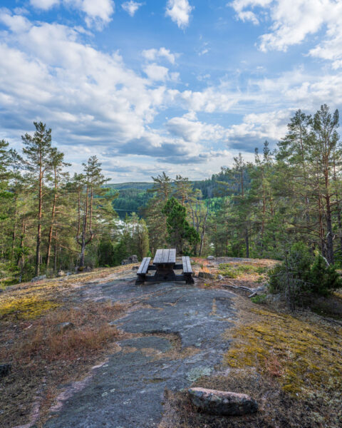 Rastplats med bänkbord på en bergshäll i Idhults naturreservat med utsikt över skogslandskap i Kinda kommun, Östergötland