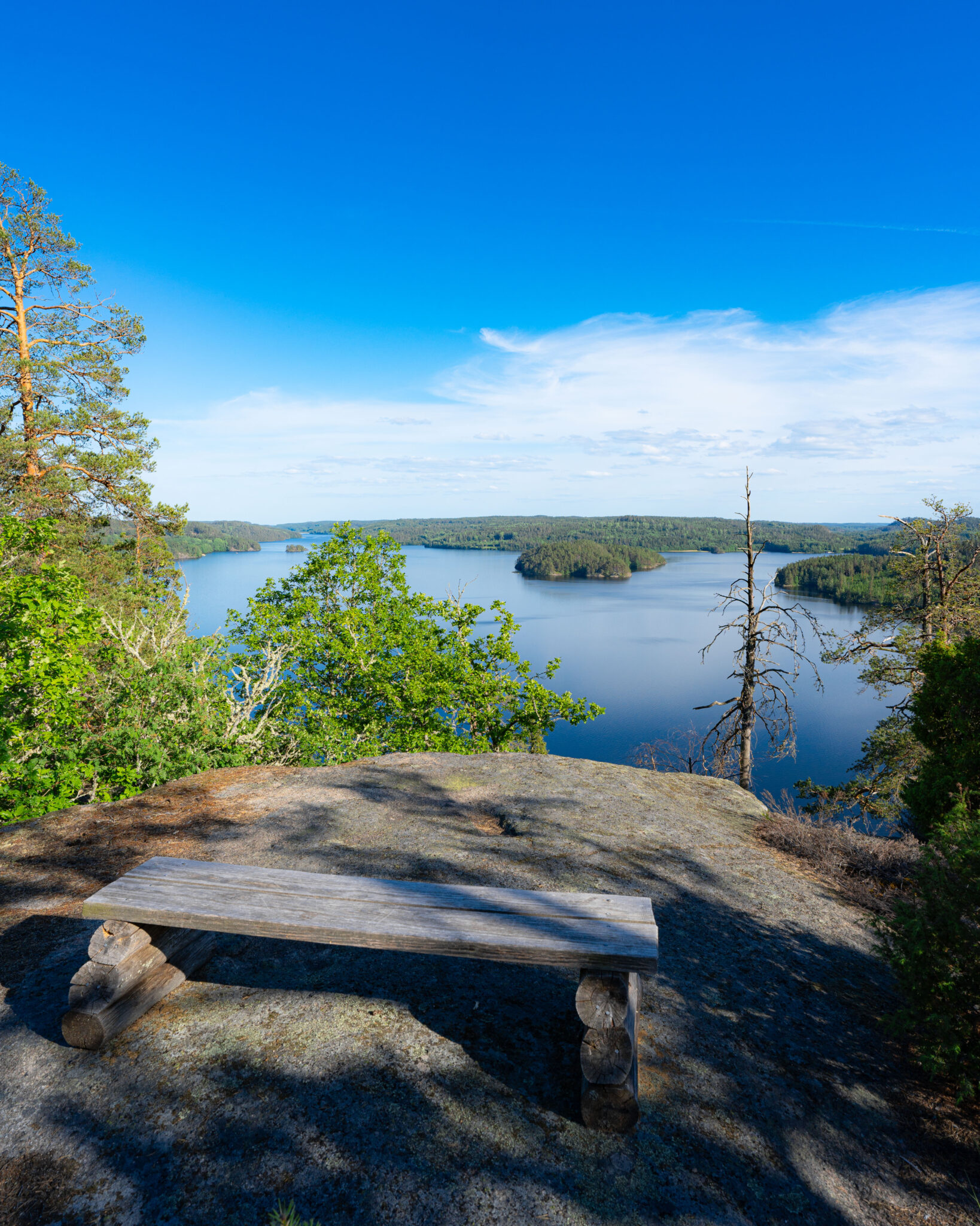 Träbänk på utsiktsplatsen på Bråtberget med panoramavy över sjön Björkern och skogsklädda öar i Kinda kommun, Östergötland