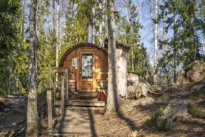 Tunnformad bastu i trä med skorsten, omgiven av blandskog vid Övre Glottern längs Glotternleden i Norrköpings kommun