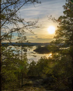 Utsikt över sjön Åsunden från Boda naturreservat i Kinda, med skogsklädda öar och solnedgång speglad i det stilla vattnet