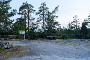 Parkeringsplats med informationstavla och picknickbord bland tallar vid Kvädöfjärdens fågeltorn.