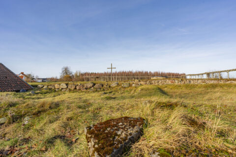 Ruinerna efter Skänninge nunnekloster (St:a Ingrids Kloster) med stenmursrester, gräsbevuxna grunder och ett träkors i bakgrunden