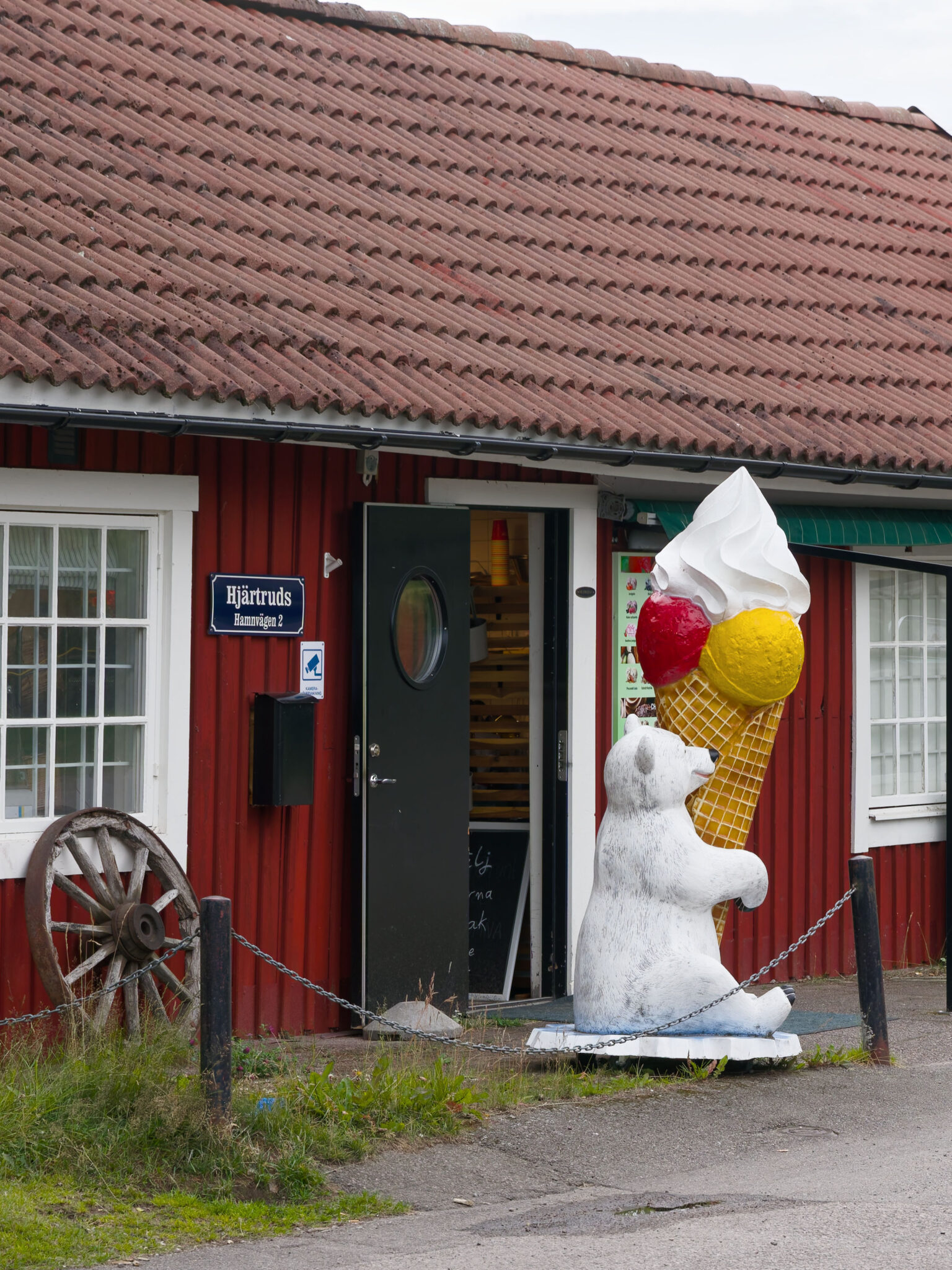 Stor glassfigur med isbjörn håller upp en jätteglass utanför det rödmålade huset i Tranås.