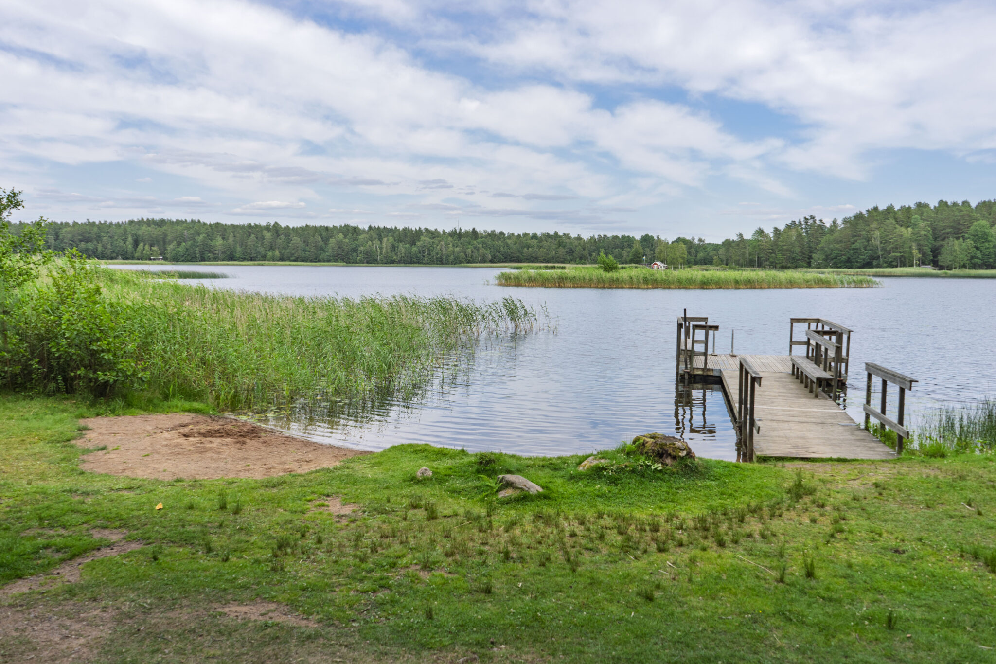 Träbrygga vid sjön Illern omgiven av vassar och grön natur i Tranås kommun, Småland.