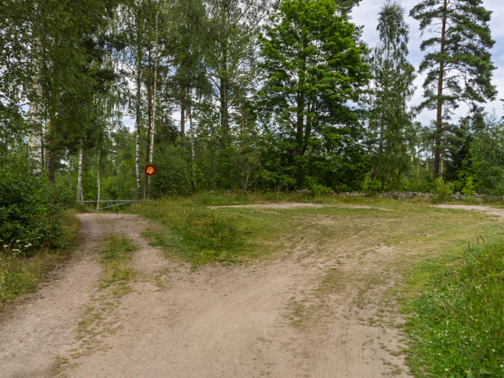 Grusad parkeringplats vid skogsbryn med björkar och tallar vid sjön Illern i Tranås kommun, Småland.