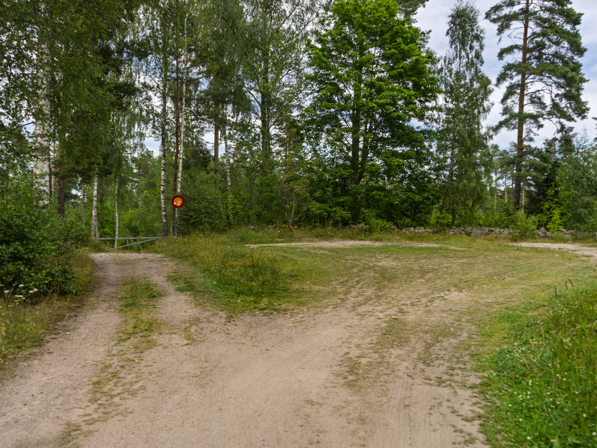 Grusad parkeringplats vid skogsbryn med björkar och tallar vid sjön Illern i Tranås kommun, Småland.