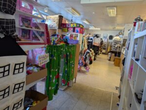 Interiör från Ture Lång's återbruk i Skänninge med hyllor fyllda av leksaker, textilier, kläder och prylar i en rymlig secondhandbutik