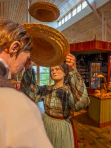 Vaxfigurer i historiska kläder håller upp halmhattar inne på Halmens Hus i Bengtsfors, Dalsland.