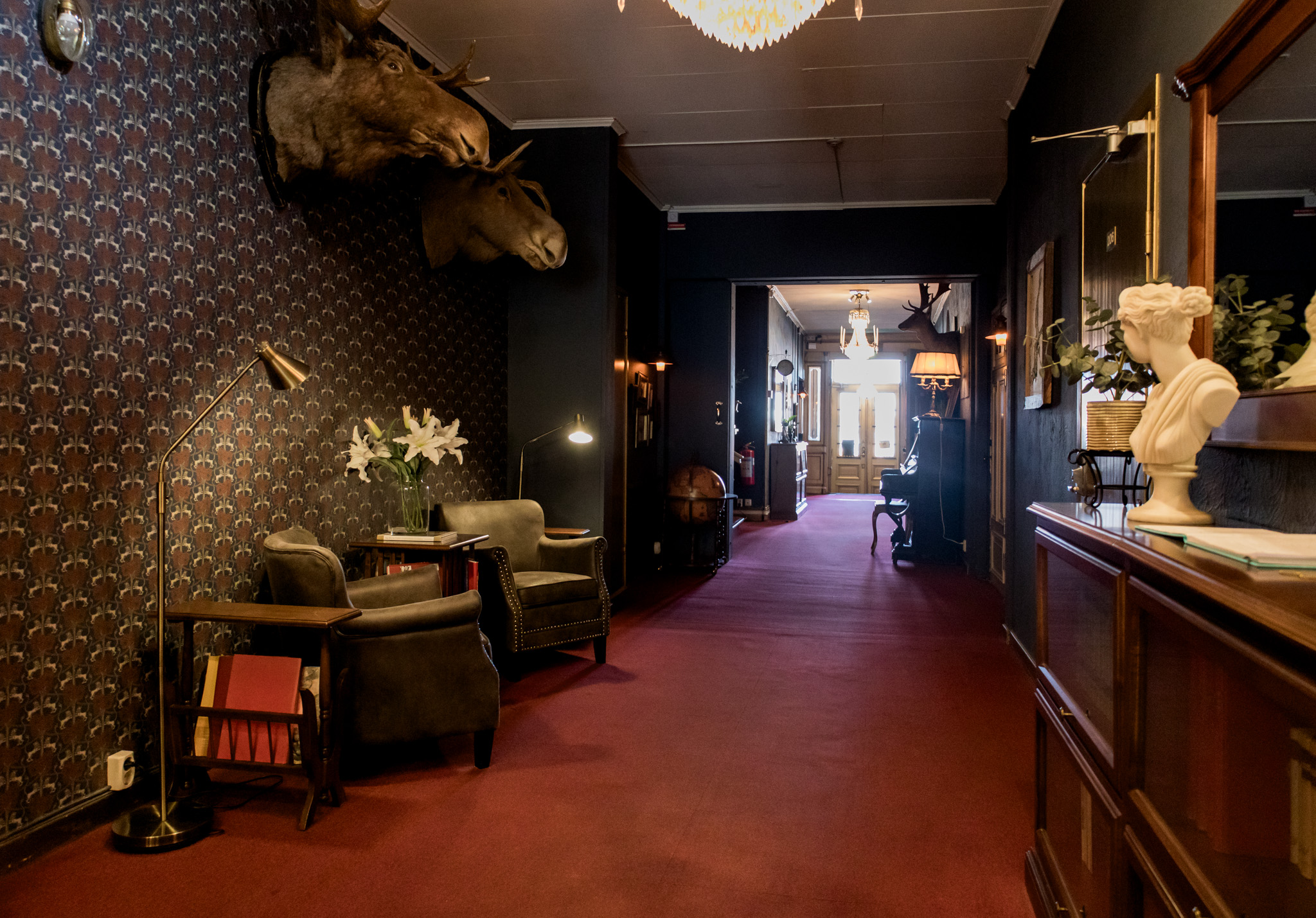 hotellreception med röd heltäckningsmatta och mörka färger